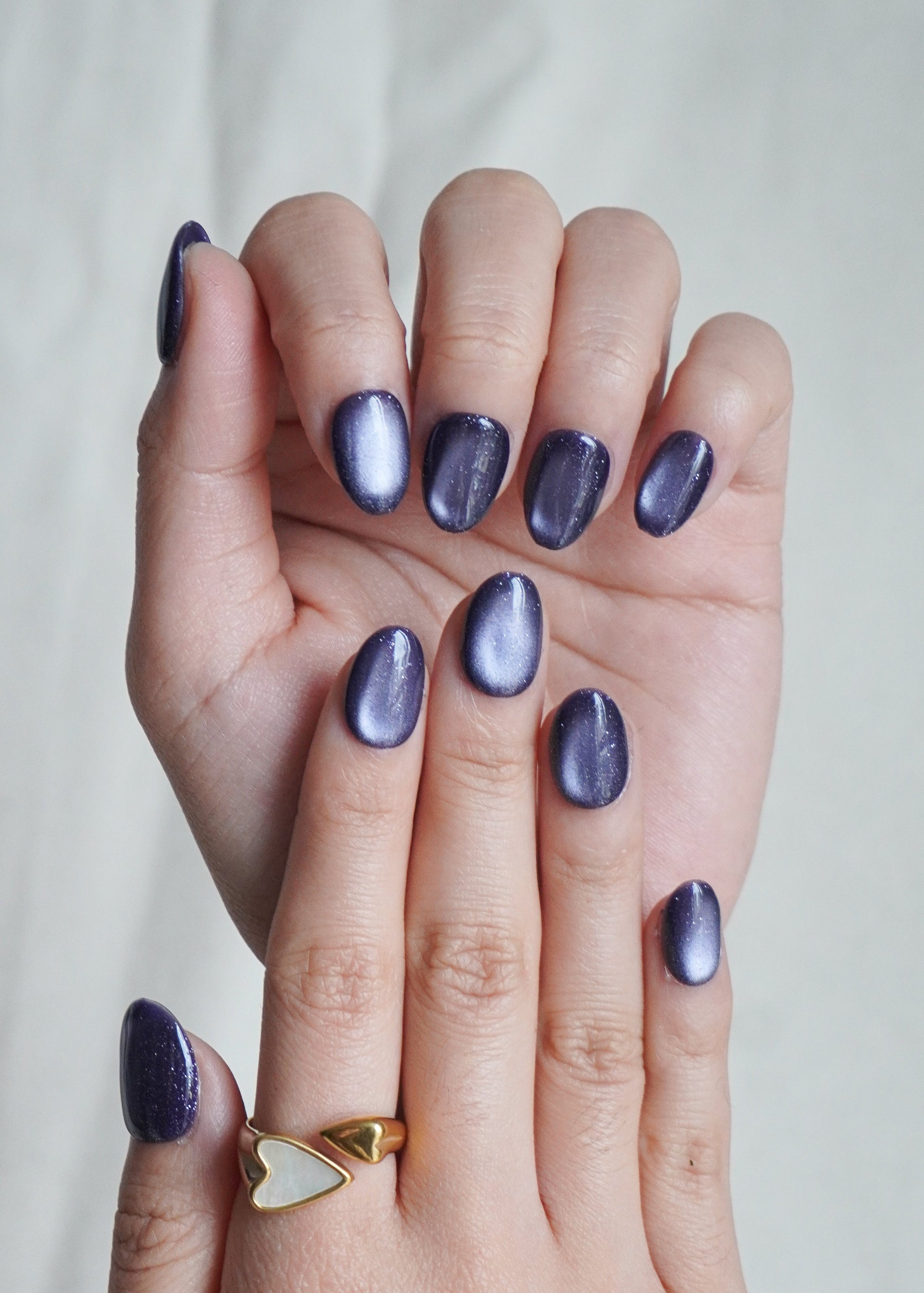 Hand with purple nail polish on a plain background