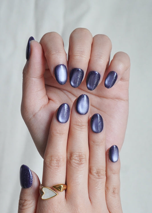 Hand with purple nail polish on a plain background