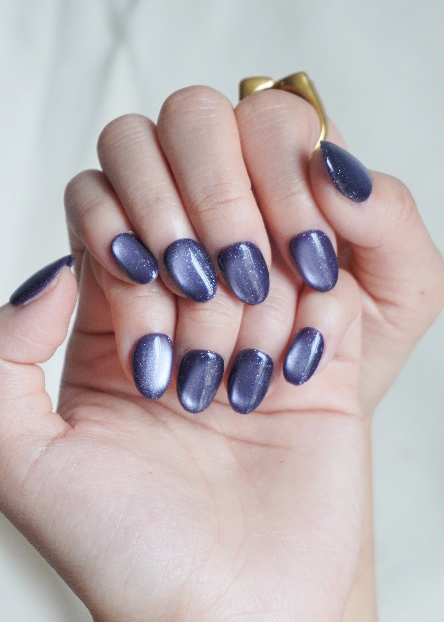 Hand with purple nail polish on a plain background