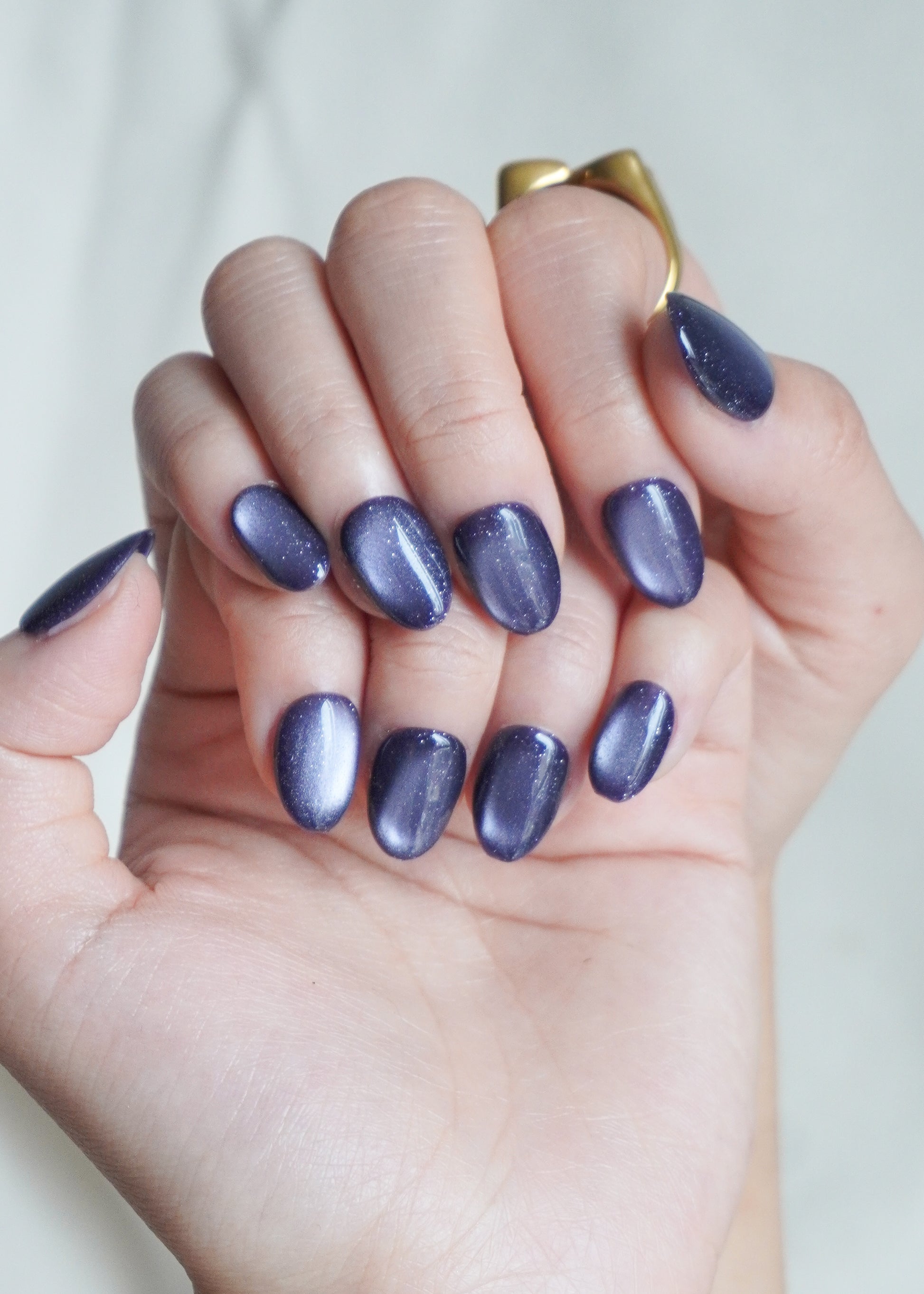 Hand with purple nail polish on a plain background